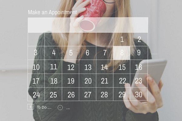 Woman drinking from a mug whilst looking at a calendar on screen